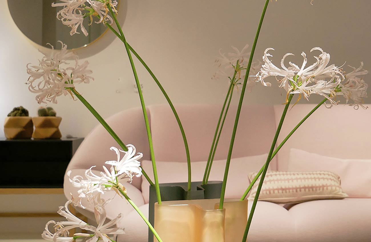 A vase with flowers in it sitting on top of a pink couch.