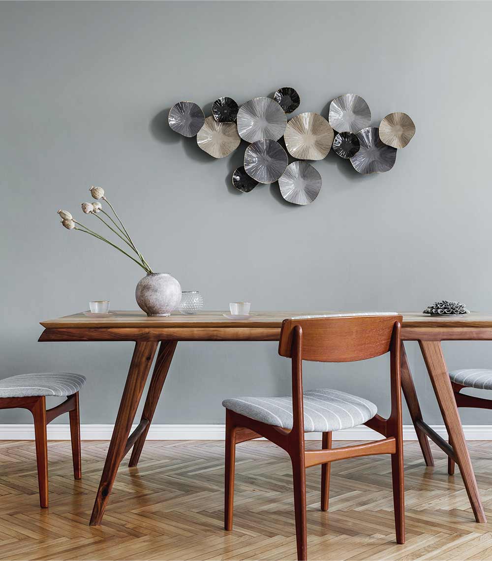 A dining room table with chairs and a vase on the floor.