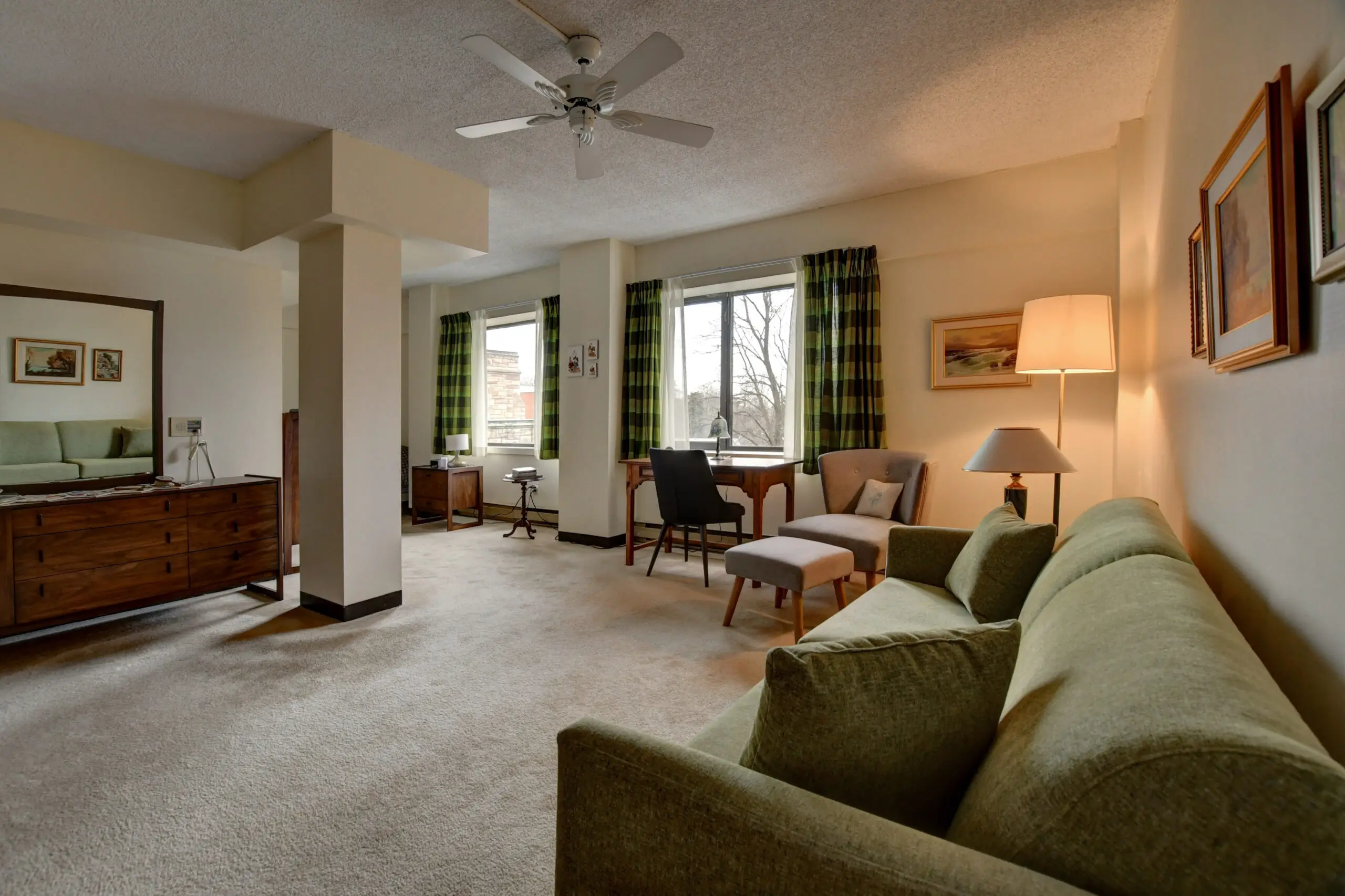 A living room with green furniture and white walls.